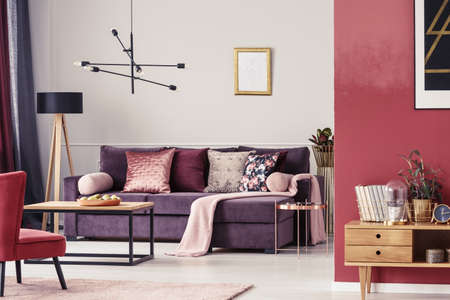 Maroon living room interior with ultra violet sofa, patterned pillows and golden frame on the wallの写真素材