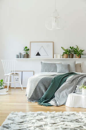Bedroom interior with king-size bed, rug, chair, ornaments and wooden floor
