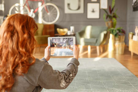 Ginger girl taking a photo of a living room interior with a tablet for her blog