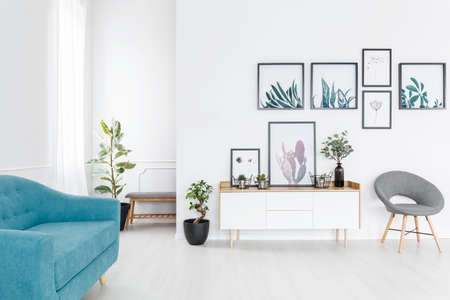Simple posters gallery hanging on white wall in elegant living room interior with blue sofaの写真素材