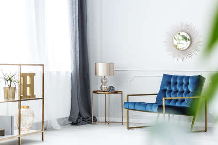 White, elegant hotel room interior with dark blue armchair and window with drapesの写真素材