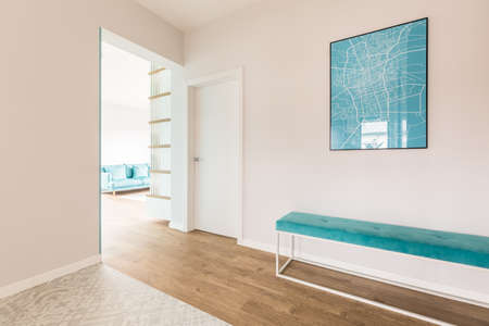 Simple hall with a blue map and bench and living room interior in the background