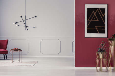 Plants in gold pots against red wall with black poster in living room with copy space on white wallの写真素材