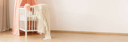 Knit blanket on white crib in pink girl's bedroom interior with copy space on the wallの写真素材