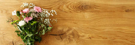 Top view of beautiful handmade bouquet of fresh flowers for Mother's Day placed on wooden table with empty space for your productの写真素材