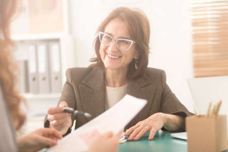 Smiling personal health coach sitting in an office and talking to a womanの写真素材