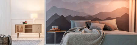 Mountain wallpaper in open space bedroom interior with king-size bed and wooden cupboardの写真素材