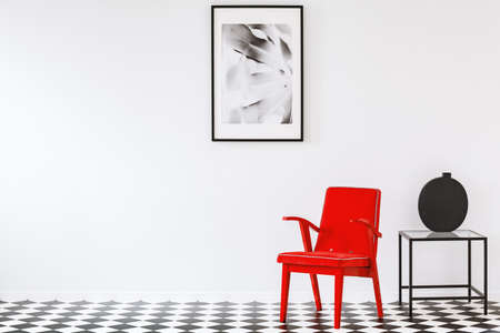 Bright red armchair in a black and white minimalist living room interior of an art loverの写真素材