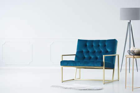 Industrial interior with armchair, lamp and a basket on the table against white, empty wall
