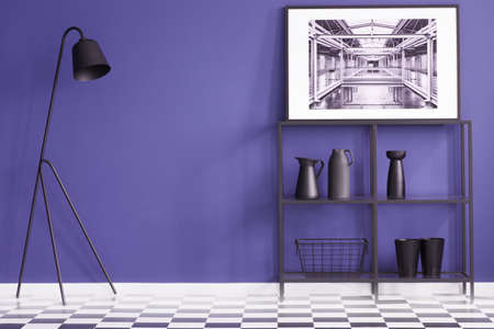 Purple living room with black furniture standing on a checkered floor and a white poster of a factory interior. Real photoの写真素材