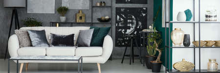 Light grey sofa with decorative pillows placed in industrial living room interior with textured wall...