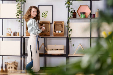 Smiling saleswoman arranging natural healthcare products on wooden boxes in the shopの写真素材
