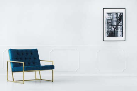Empty interior with blue armchair and a poster on the wall