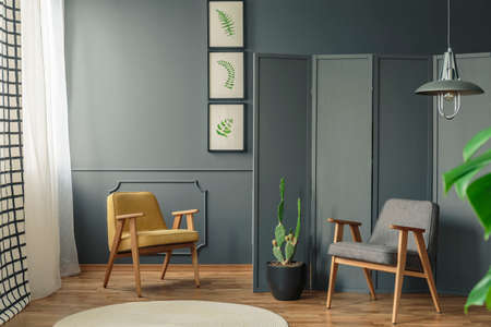 Two chairs in a room interior with grey walls and wooden floor