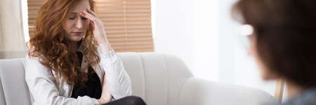 Stressed woman holding her head during therapy with counselorの写真素材