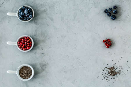 Top view of a symmetrical arrangement of blueberries, pomegranate and seeds on a gray table.の写真素材
