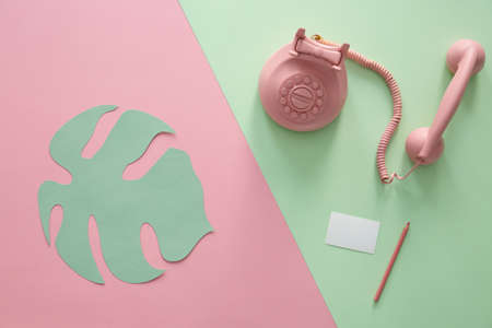 Vintage phone and paper leaf on a duotone, pink and green backgroundの写真素材