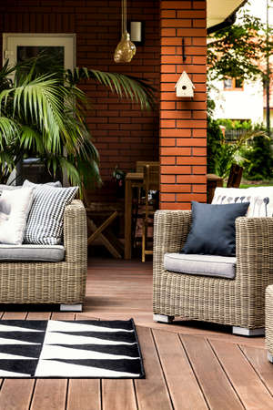 Wooden terrace of a summer house with comfy rattan armchair and sofa