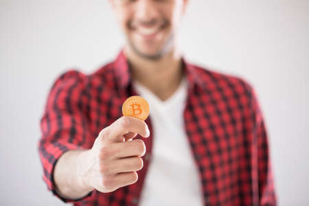 Close-up of man holding gold BitCoin - digital cryptocurrency