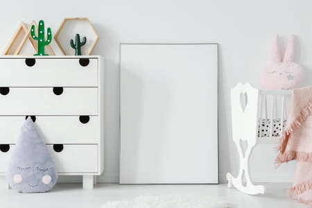 Poster with mockup between white cradle and cabinet in child's room interior. Real photo. Place for your posterの写真素材