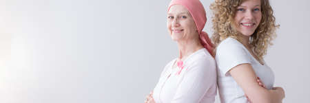 Panorama of happy daughter and mother with cancer against grey background with copy spaceの写真素材