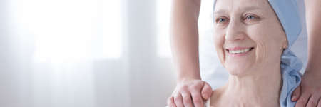 Panorama of smiling sick senior woman supported by a caregiver in a cancer hospiceの写真素材