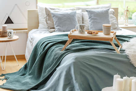King-size bed with white and grey bedding and a breakfast tray in bedroom interiorの写真素材