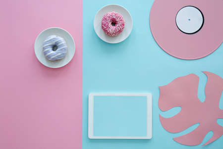 Blue doughnut on pink background and mockup of tablet next to a leaf and vinylの写真素材