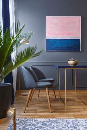 Real photo of dining room interior with two chairs standing in front of a table on a wooden floor...