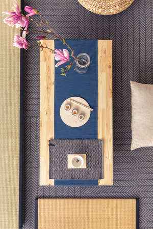 Top view of a Japanese table with sushi and flowers next to tatami mats and pillowsの写真素材