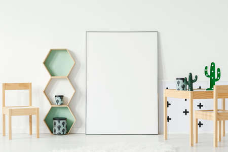 Chair at wooden table with cactus in child's room interior with mockup of empty poster. Real photo with a place for your posterの写真素材