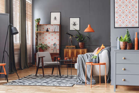 Retro living room interior with an armchair, coffee table, wooden cupboard, lamps and posters