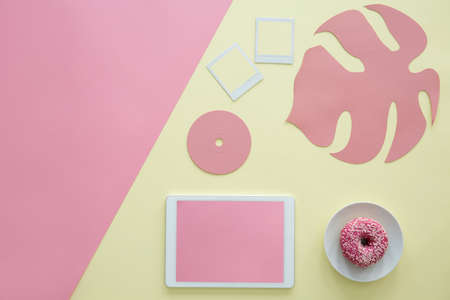 Copy space on pink background next to a tablet, doughnut and disc on yellow backgroundの写真素材