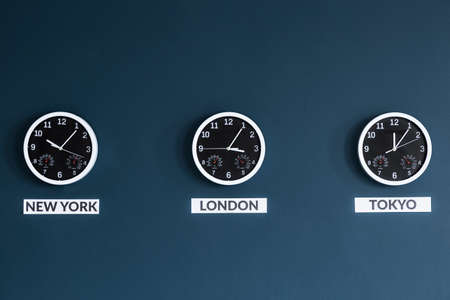 Black clocks on navy blue wall in businessman's home office interiorの写真素材