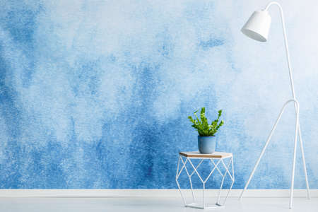 Empty wall for product placement, stool with a plant and white lamp in living room interiorの写真素材