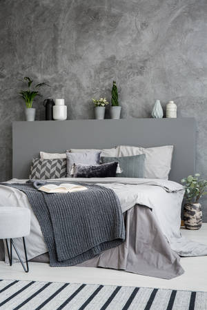 Dark blanket on bed with headboard in grey bedroom interior with concrete wall. Real photoの写真素材