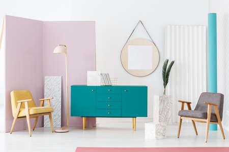 Modern living room interior with two armchairs, pastel pink lamp, turquoise cupboard and decorative...