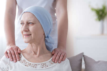 Smiling elderly woman with cancer in remission supported by her daughterの写真素材
