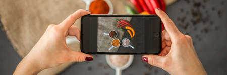 Top view of woman holding a phone and taking a photo of healthy food for her culinary blog