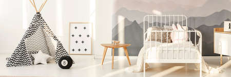 Patterned tent near white metal bed in kid's bedroom interior with mountain wallpaperの写真素材