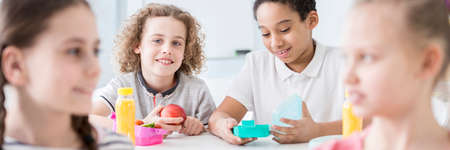 Panorama of pupils eating lunch in the classroom during a break. Blurred faces of girls in the...
