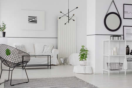 Black round frame on the wall in modern living room interior with armchair near white couch