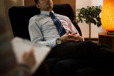 Close-up of burnt-out corporate employee during therapy with advisorの写真素材