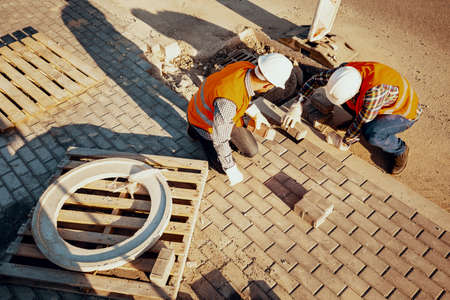 High angle of physical workers in reflective vests arranging a paving stonesの写真素材