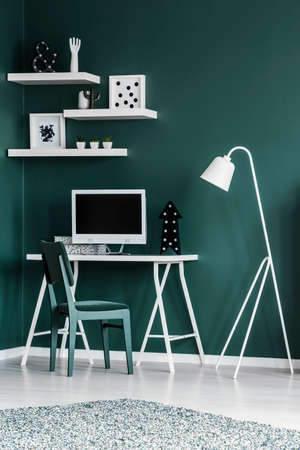 Simple home office interior with a chair, desk, computer with empty screen, lamp and shelves. Place your graphic hereの写真素材
