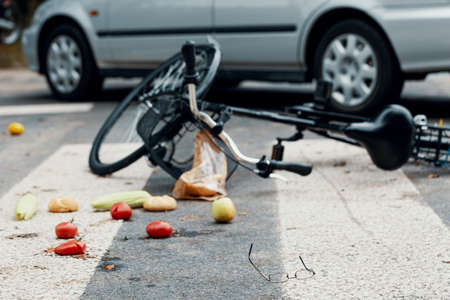 Broken bike and vegetables on pedestrian crossing after a traffic incident with a carの写真素材
