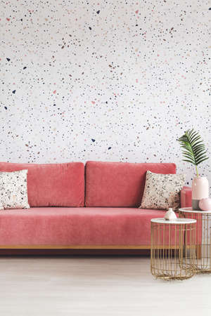 Gold table in front of pink sofa with patterned cushions in modern living room interior. Real photoの写真素材