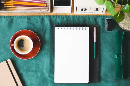 Top view on red cup of coffee and notes with copy space on green background. Real photo with an...