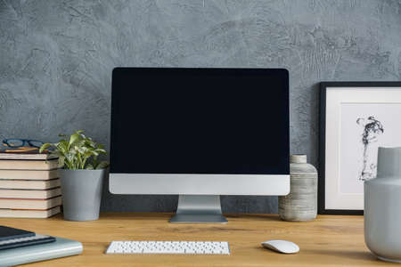 Mockup of desktop computer on wooden desk with plant in grey workspace interior. Real photoの写真素材