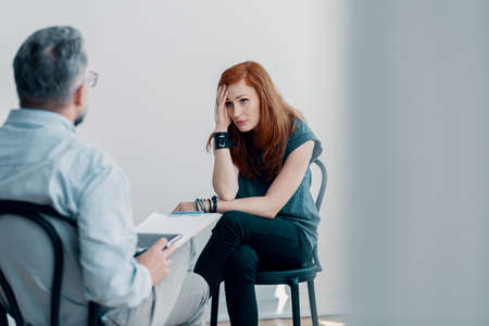 Scared young woman talking to a therapist about abuse in a bright officeの写真素材